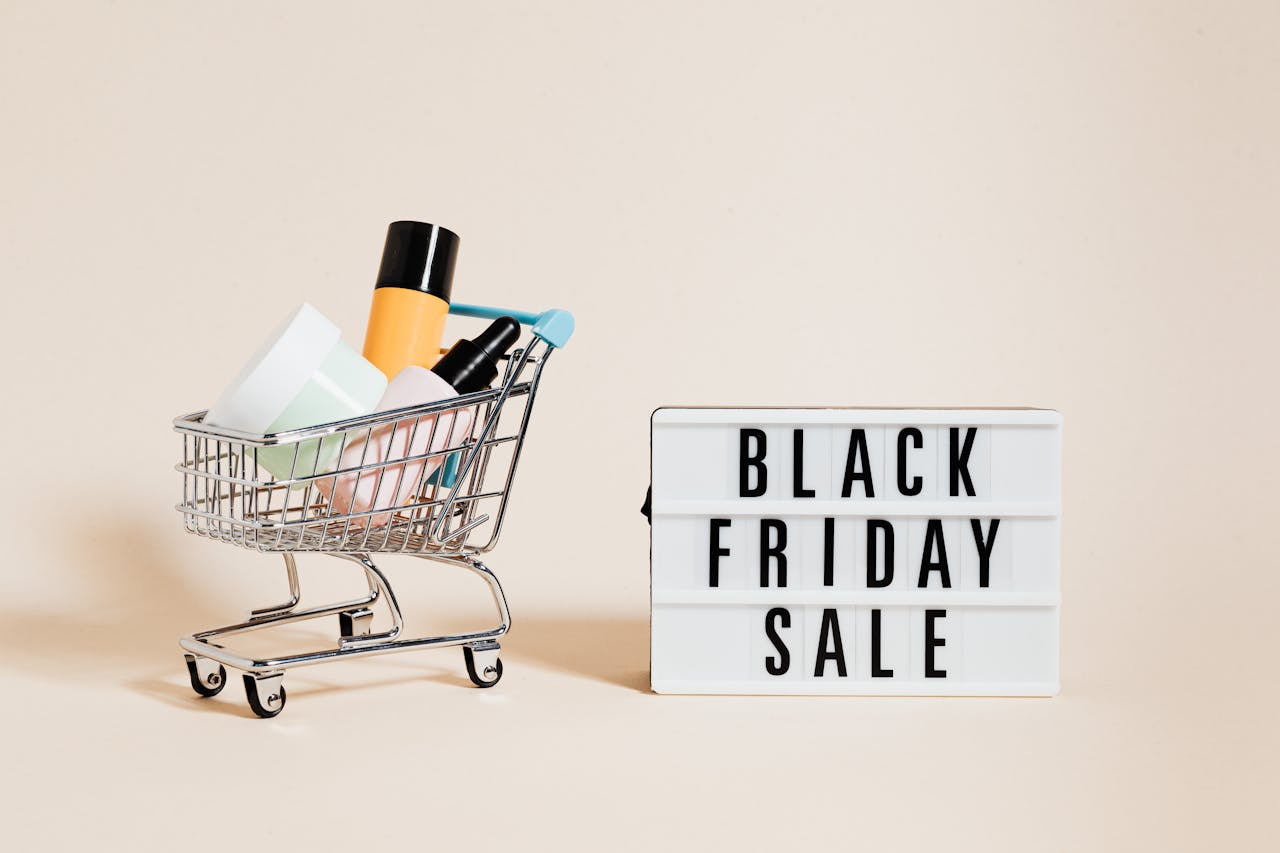 Products in a Shopping Cart Beside a Black Friday Sale Signage on Beige Background